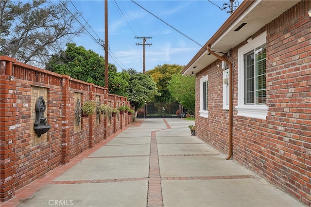 view of side of property with brick siding, a patio area, and fence
