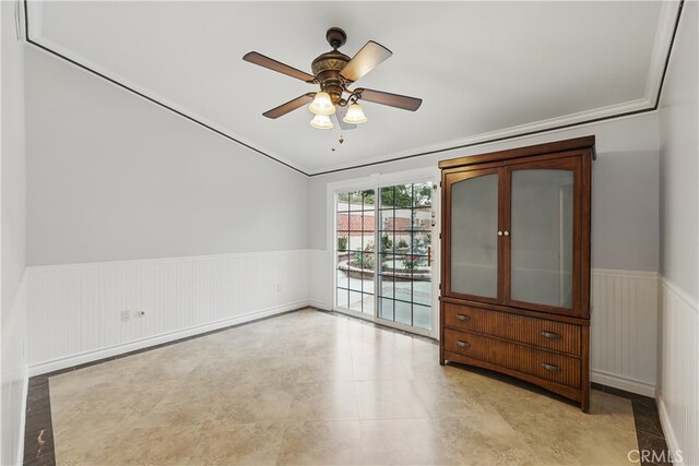 empty room featuring a ceiling fan and wainscoting
