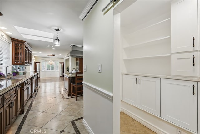 interior space with a sink, a skylight, light tile patterned floors, an inviting chandelier, and recessed lighting