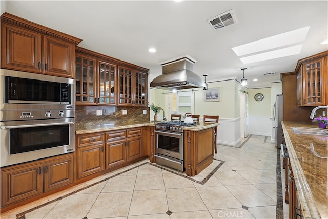 kitchen featuring island exhaust hood, visible vents, a sink, a peninsula, and appliances with stainless steel finishes