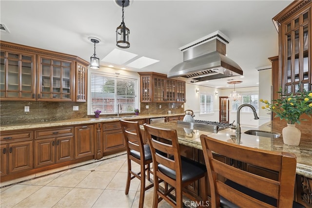 kitchen featuring backsplash, island exhaust hood, light tile patterned floors, and a sink