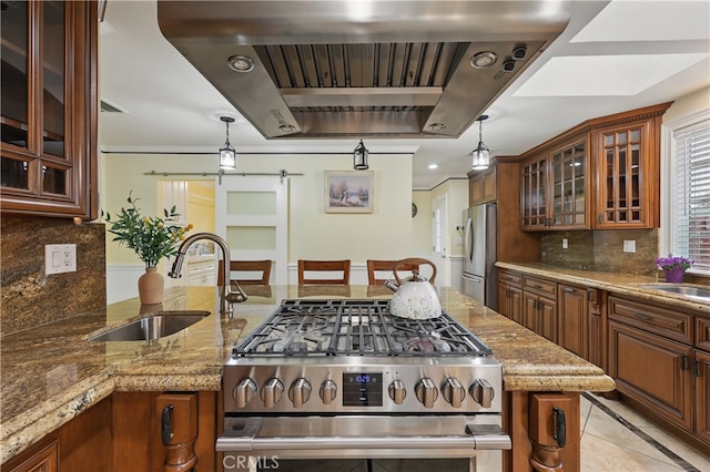 kitchen with a sink, tasteful backsplash, exhaust hood, brown cabinetry, and appliances with stainless steel finishes