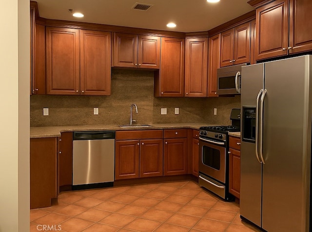 855 Wilcox Ave Unit 103, Los Angeles, CA 90038 - kitchen with stainless steel appliances, tasteful backsplash, recessed lighting, brown cabinetry, and light tile patterned flooring