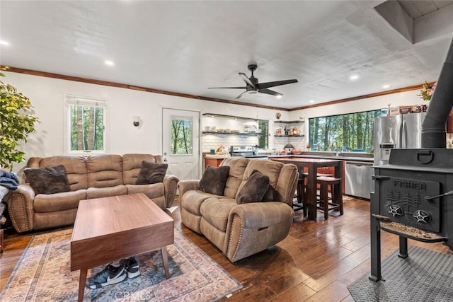 living area featuring dark wood-type flooring, ornamental molding, and ceiling fan