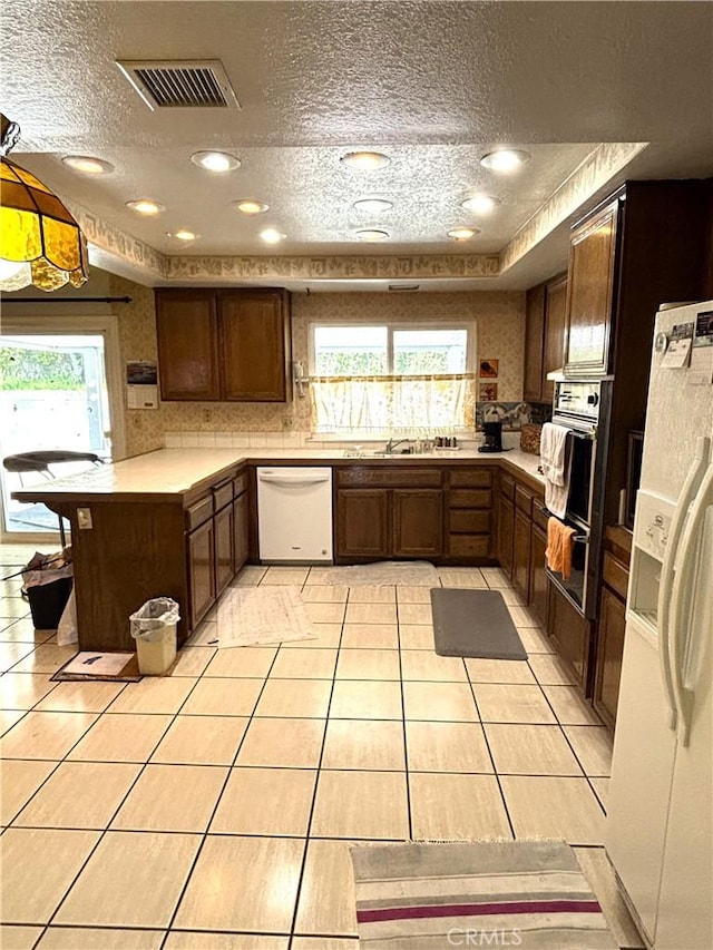 1193 W Molly Ct, Upland, CA 91786 - kitchen with light countertops, visible vents, a healthy amount of sunlight, white appliances, and a textured ceiling