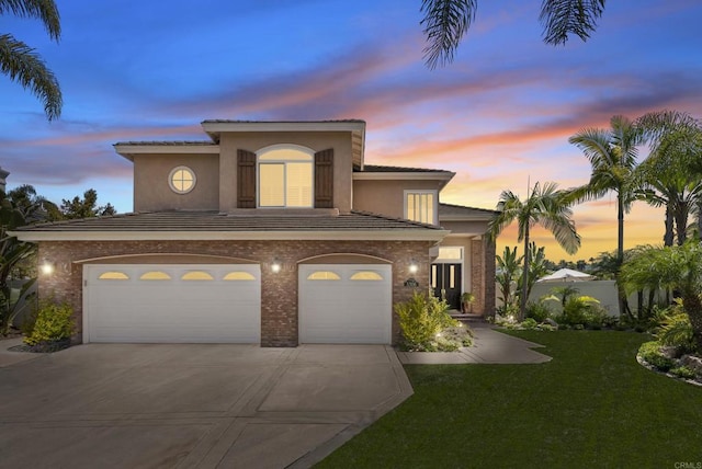mediterranean / spanish home with stucco siding, a front lawn, a garage, and concrete driveway