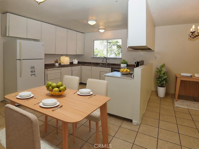 kitchen featuring dark countertops, a sink, light tile patterned floors, white cabinets, and freestanding refrigerator