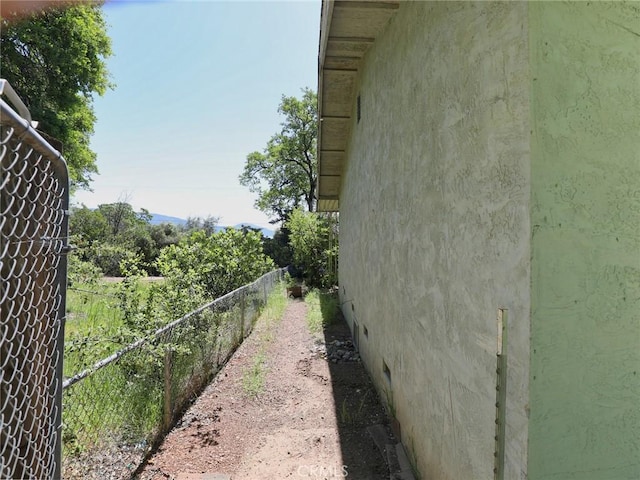 view of side of home featuring stucco siding and fence