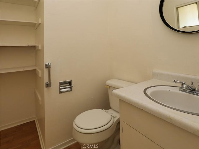 bathroom featuring baseboards, wood finished floors, vanity, and toilet