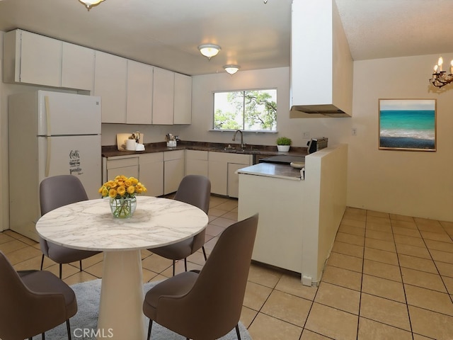 kitchen featuring dark countertops, a sink, light tile patterned floors, white cabinets, and freestanding refrigerator