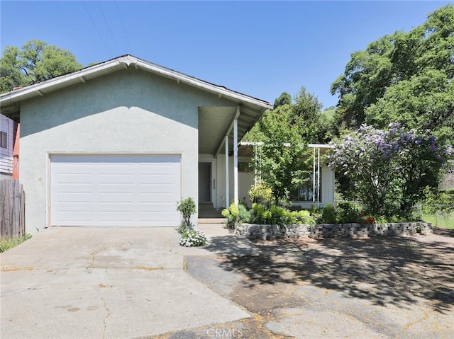 ranch-style house featuring an attached garage, driveway, fence, and stucco siding