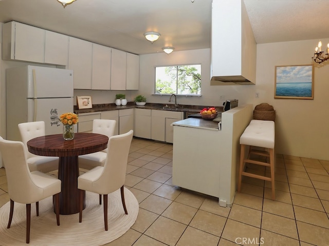 kitchen featuring dark countertops, light tile patterned flooring, a chandelier, white cabinets, and freestanding refrigerator