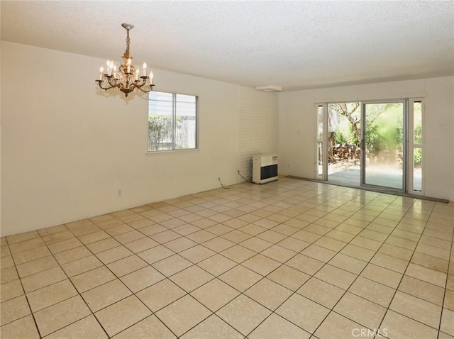 spare room with a chandelier, heating unit, and a textured ceiling