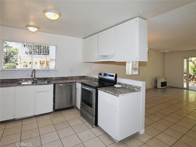 kitchen featuring dark countertops, light tile patterned floors, stainless steel appliances, and a sink
