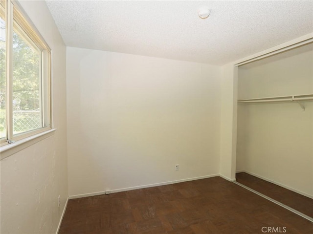 unfurnished bedroom featuring a closet, baseboards, and multiple windows