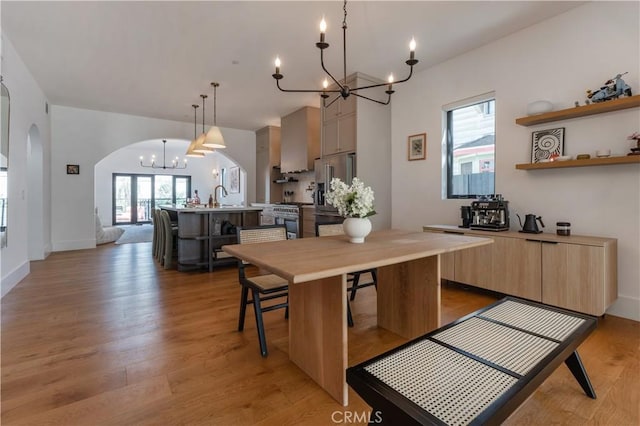 5142 Brynhurst Ave, Los Angeles, CA 90043 - dining space featuring light wood finished floors, baseboards, arched walkways, and a notable chandelier