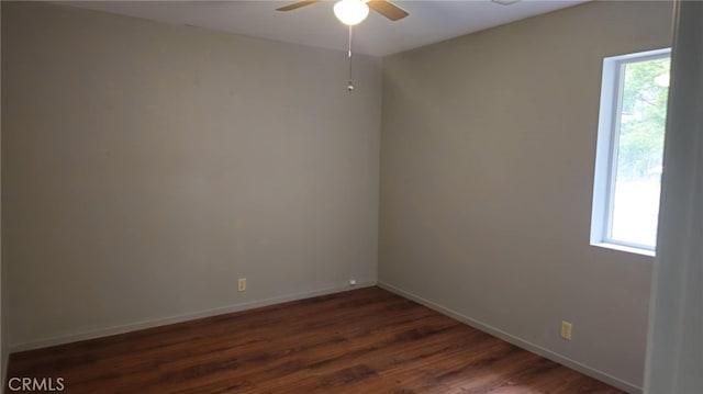 unfurnished room with a ceiling fan, baseboards, and dark wood-style flooring