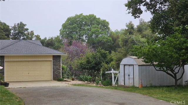 garage with aphalt driveway and a shed