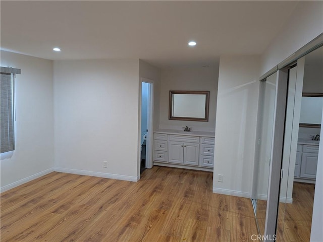 unfurnished bedroom with light wood-style flooring, baseboards, recessed lighting, and a sink