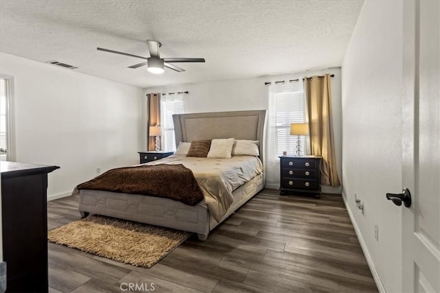 bedroom featuring visible vents, a textured ceiling, multiple windows, and dark wood-type flooring