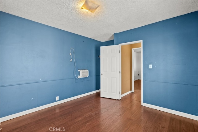 15430 Parthenia St, North Hills, CA 91343 - unfurnished bedroom featuring baseboards, wood finished floors, a textured ceiling, and a wall mounted air conditioner