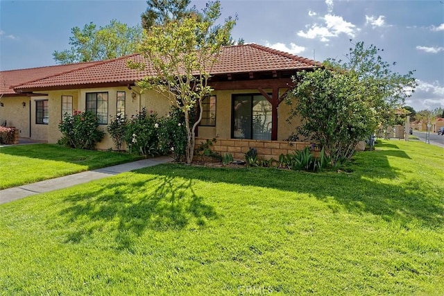 view of front facade featuring a tiled roof, a front yard, and stucco siding