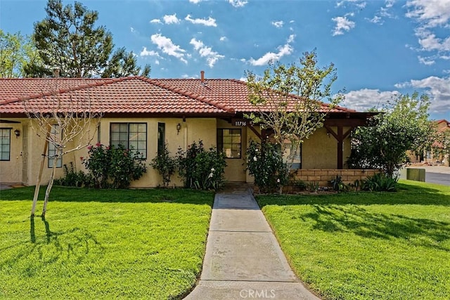 view of front of house with a front lawn, a tiled roof, and stucco siding