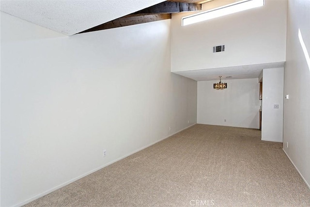 empty room with a notable chandelier, visible vents, high vaulted ceiling, and light carpet