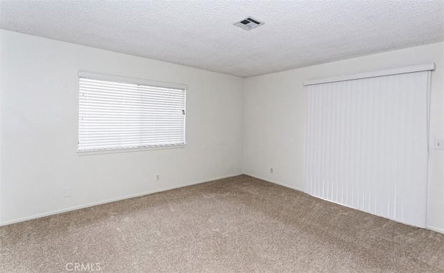 carpeted spare room with a textured ceiling and visible vents