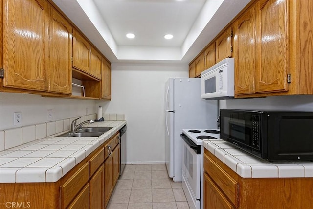 kitchen featuring baseboards, tile countertops, a sink, and white appliances