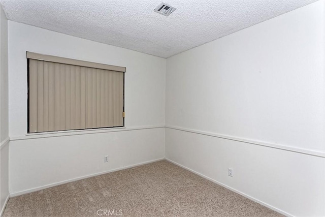 spare room featuring a textured ceiling, visible vents, carpet flooring, and baseboards