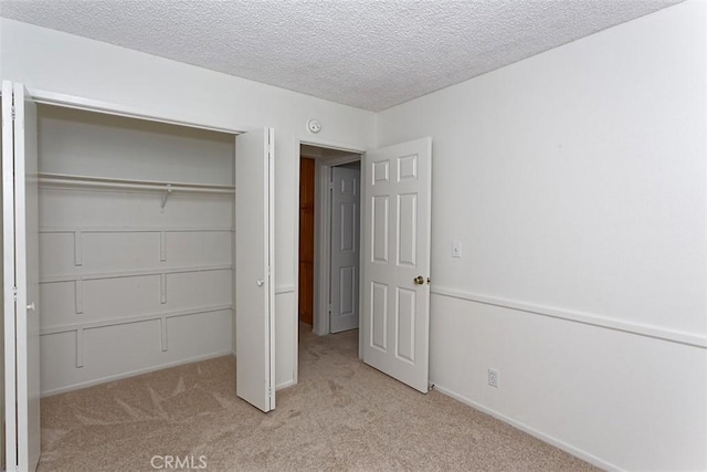 unfurnished bedroom with a textured ceiling, baseboards, carpet floors, and a closet