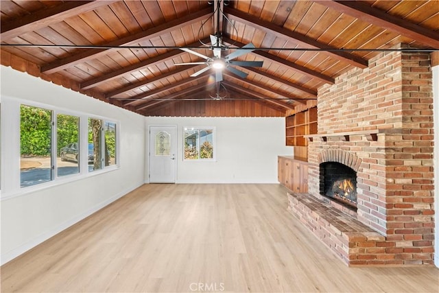 unfurnished living room featuring wood finished floors, lofted ceiling with beams, ceiling fan, baseboards, and a brick fireplace