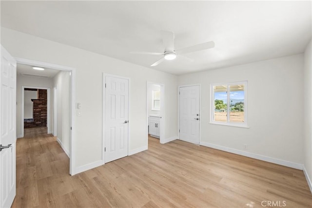 unfurnished bedroom featuring ensuite bath, ceiling fan, baseboards, and light wood finished floors