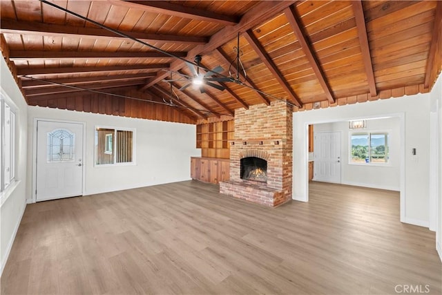 unfurnished living room featuring vaulted ceiling with beams, a ceiling fan, wood finished floors, a brick fireplace, and wood ceiling