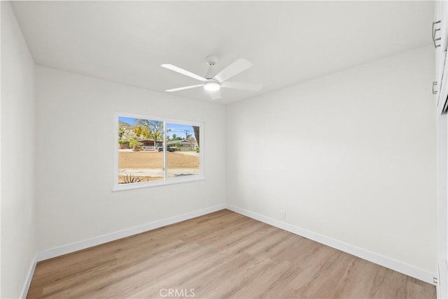 spare room with baseboards, a ceiling fan, and light wood-style floors