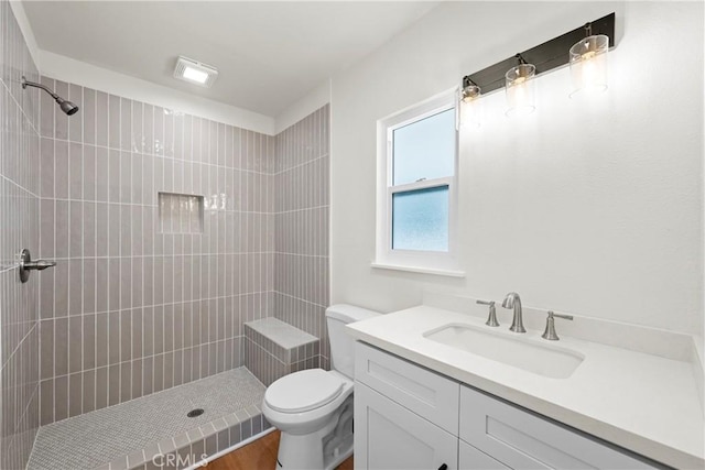 full bath with a tile shower, toilet, and vanity
