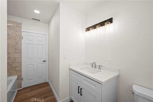 bathroom featuring wood finished floors, visible vents, toilet, and vanity