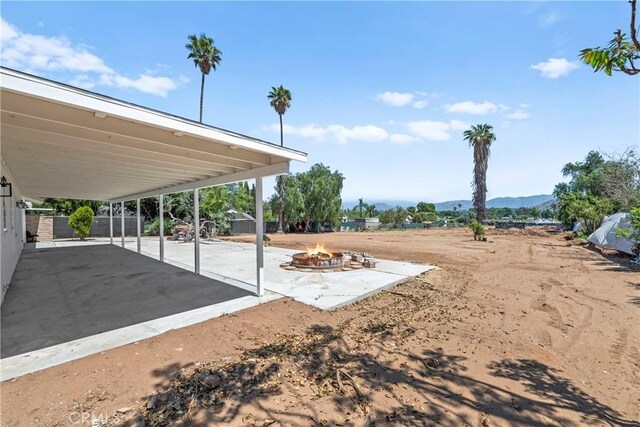 exterior space featuring a fire pit, a mountain view, and fence