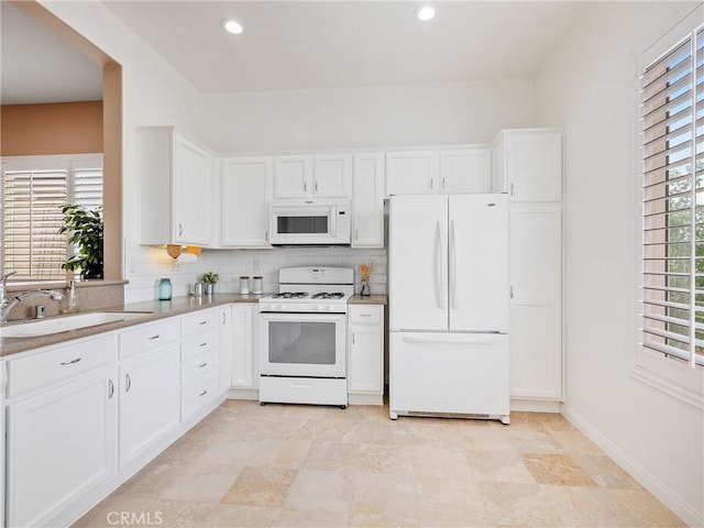 kitchen with white cabinetry, baseboards, a sink, and white appliances