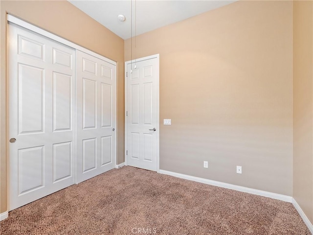 unfurnished bedroom with carpet floors, a closet, and baseboards