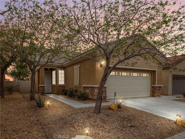 view of front of home with stone siding, concrete driveway, stucco siding, and fence