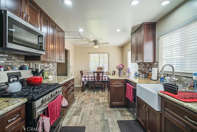 kitchen with a sink, light wood-style floors, decorative backsplash, appliances with stainless steel finishes, and ceiling fan