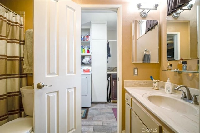 bathroom with toilet, vanity, and washer / clothes dryer