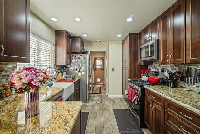 kitchen featuring recessed lighting, backsplash, light wood-style flooring, and appliances with stainless steel finishes