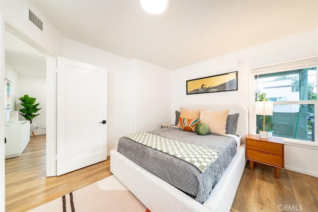 bedroom with wood finished floors, visible vents, and baseboards
