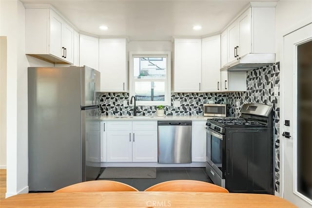 kitchen featuring under cabinet range hood, appliances with stainless steel finishes, white cabinetry, and a sink