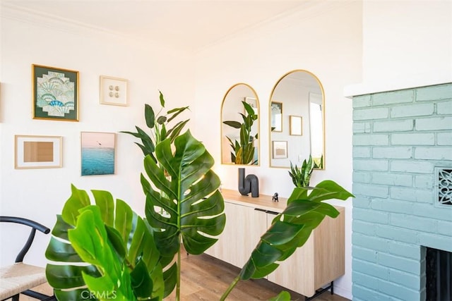 room details featuring arched walkways, wood finished floors, a brick fireplace, and ornamental molding