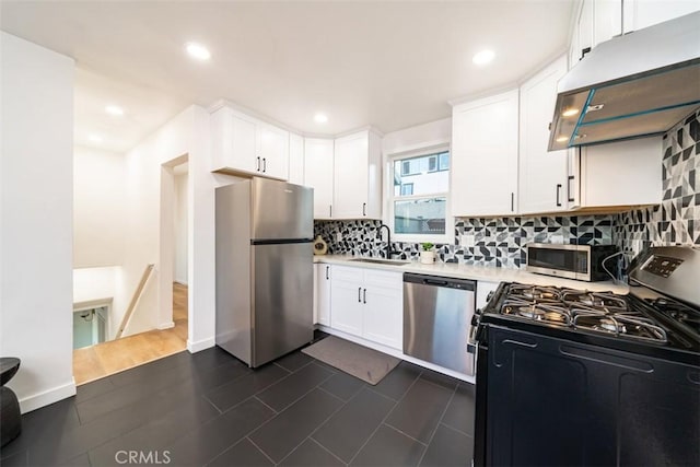 kitchen with under cabinet range hood, light countertops, a sink, tasteful backsplash, and appliances with stainless steel finishes