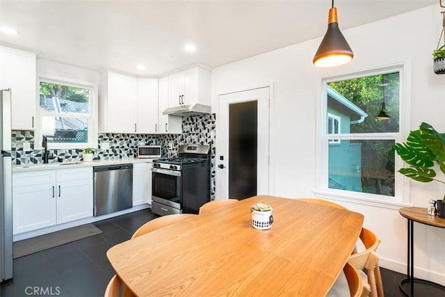 kitchen featuring white cabinets, backsplash, light countertops, a sink, and appliances with stainless steel finishes